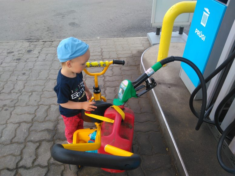 Baby is putting gas in his tricycle
